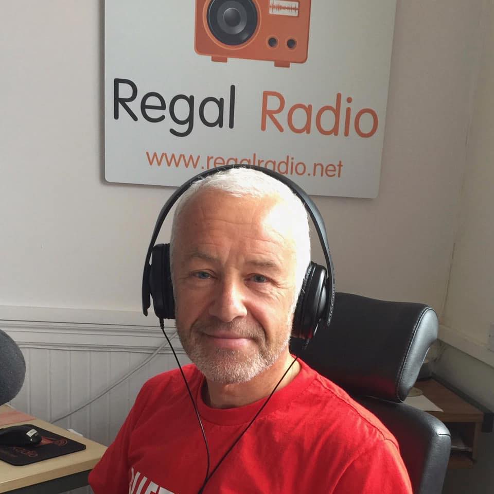 Steve sitting in the studio with headphones on, smiling at the camera.